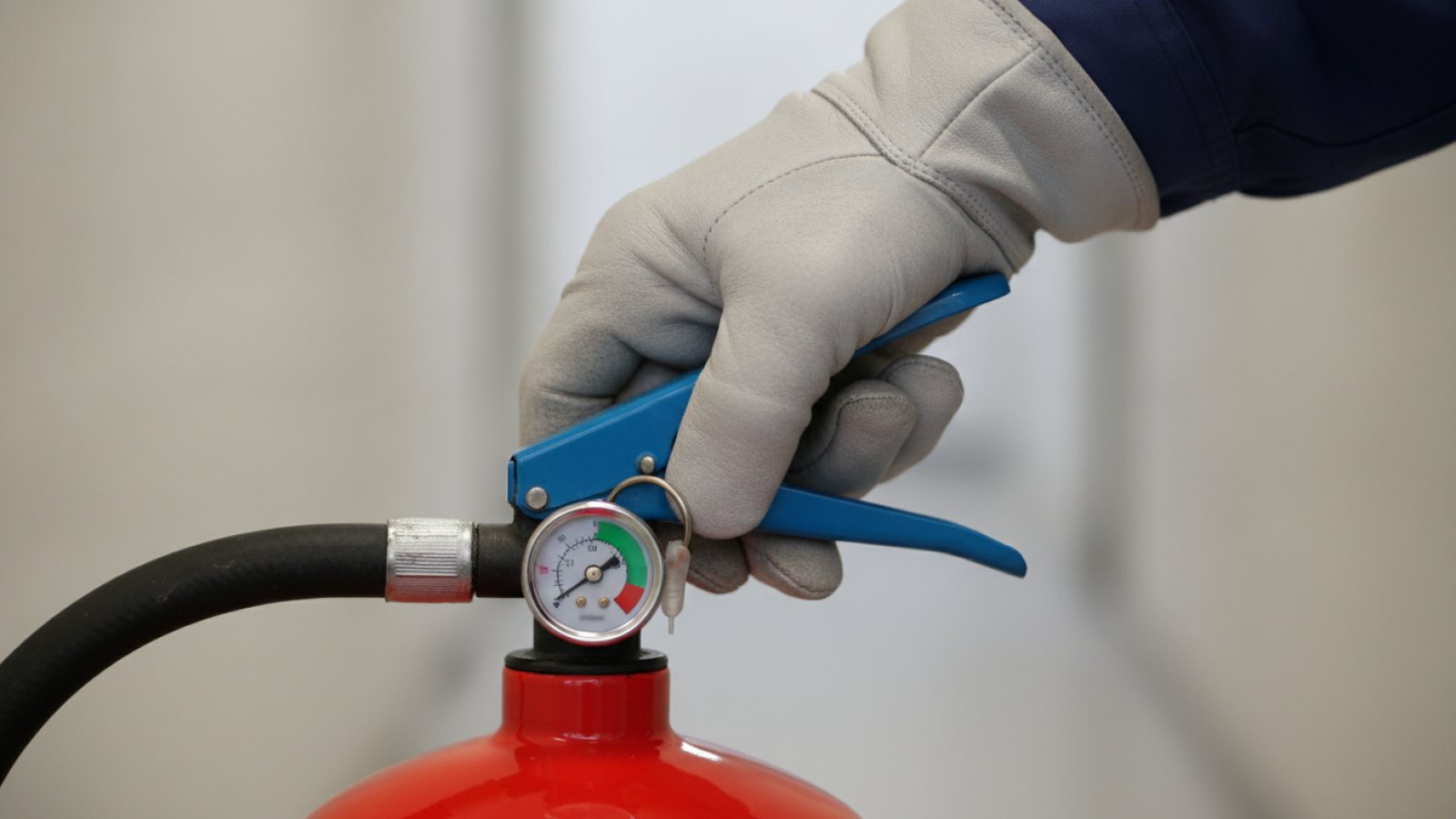 Gros plan sur la main d'un technicien qui contrôle le manomètre d'un extincteur